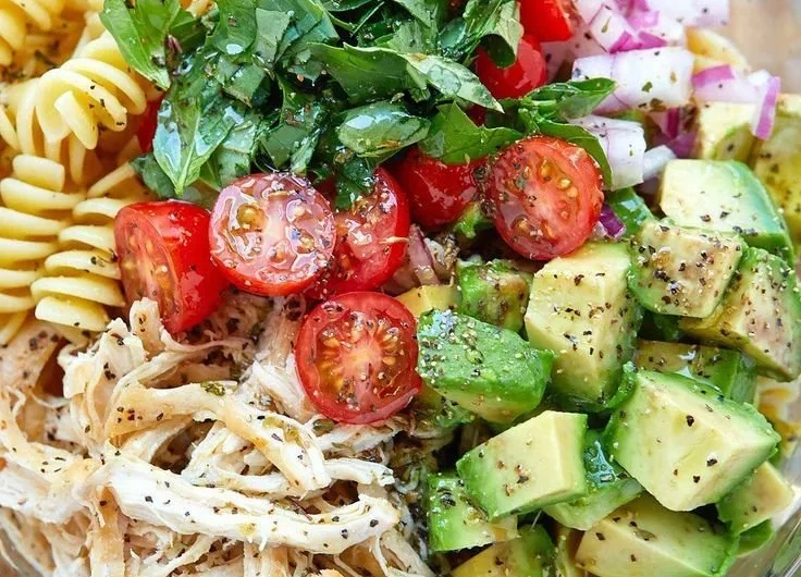 Healthy chicken pasta salad with fresh vegetables and dressing.