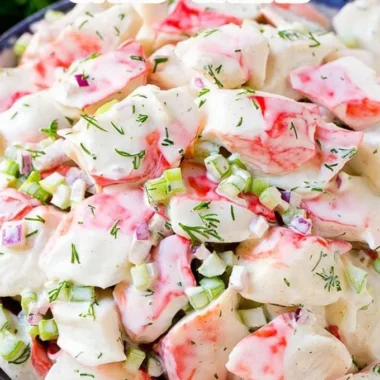 A vibrant crab salad with fresh vegetables and dressing served in a bowl.
