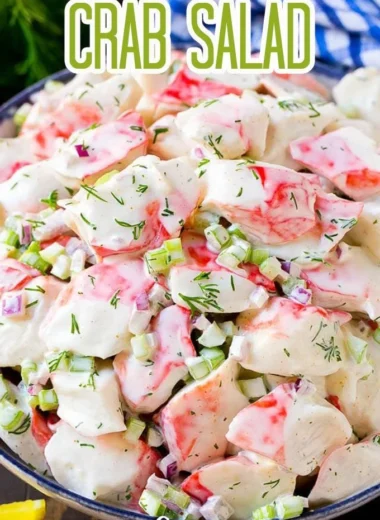 A vibrant crab salad with fresh vegetables and dressing served in a bowl.