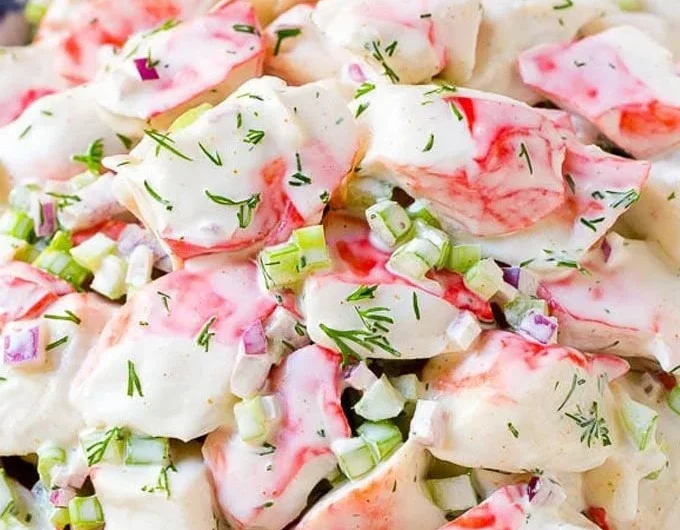 A vibrant crab salad with fresh vegetables and dressing served in a bowl.