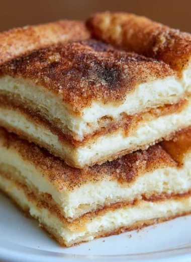 Delicious Mexican Churro Cheesecake Bars topped with cinnamon sugar and whipped cream.