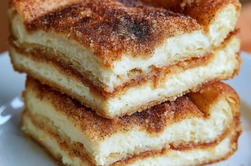 Delicious Mexican Churro Cheesecake Bars topped with cinnamon sugar and whipped cream.