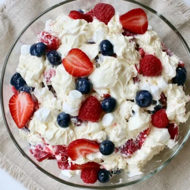 A vibrant Red White and Blue Cheesecake Salad with berries and creamy cheesecake layers.