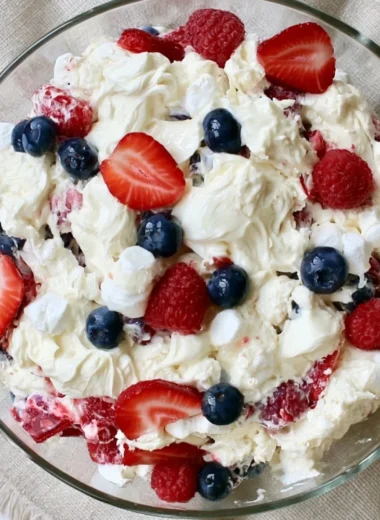 A vibrant Red White and Blue Cheesecake Salad with berries and creamy cheesecake layers.