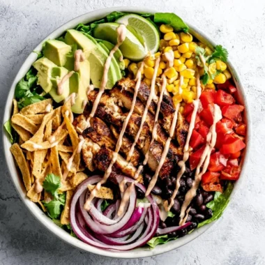 A bowl of Southwest Avocado Chicken Salad with colorful ingredients and garnishes.