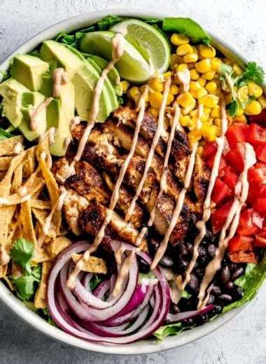A bowl of Southwest Avocado Chicken Salad with colorful ingredients and garnishes.