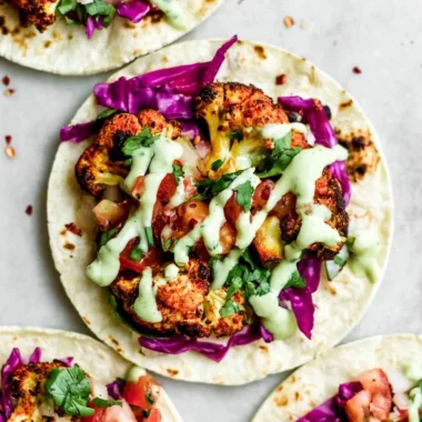 Vegan roasted cauliflower tacos topped with fresh ingredients in a taco shell