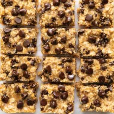 No-bake peanut butter oatmeal bars topped with chocolate chips on a wooden table.