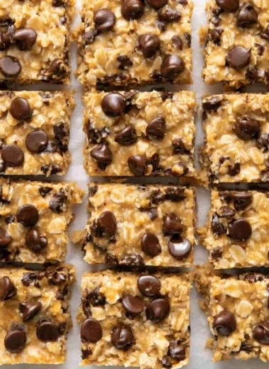 No-bake peanut butter oatmeal bars topped with chocolate chips on a wooden table.