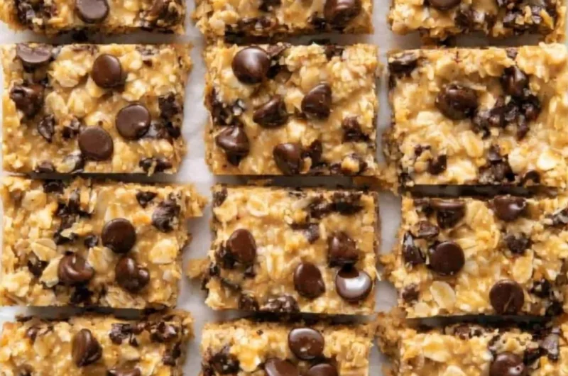 No-bake peanut butter oatmeal bars topped with chocolate chips on a wooden table.