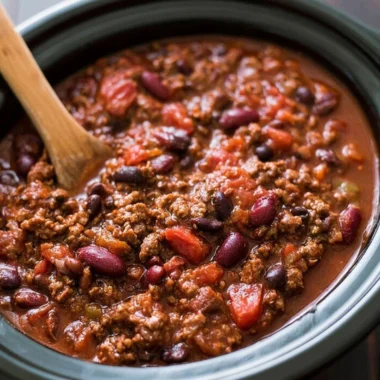 Bowl of easy slow cooker chili garnished with herbs and served with bread.