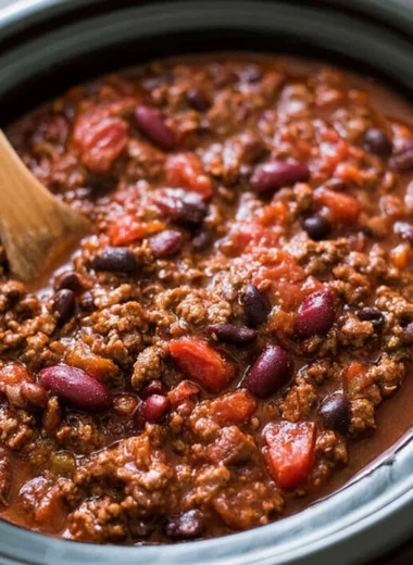 Bowl of easy slow cooker chili garnished with herbs and served with bread.