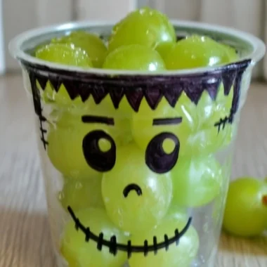 A variety of healthy Halloween snacks including fruits and veggies shaped like spooky characters