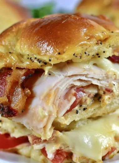 Kentucky Hot Brown Sliders topped with cheese and bacon, served on a platter.