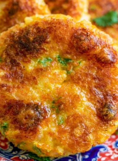Golden brown potato cutlet on a white plate garnished with herbs