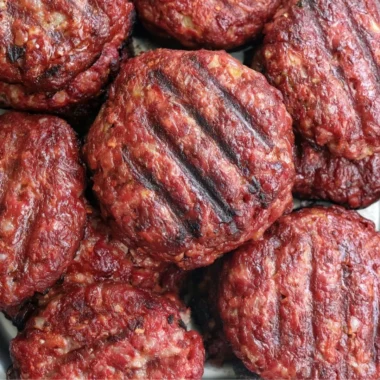 Delicious smoked burgers stacked with toppings on a plate