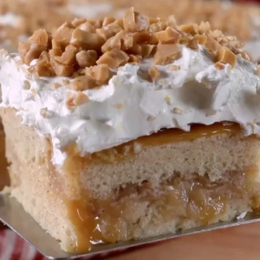 Delicious caramel apple poke cake topped with drizzled caramel and apples